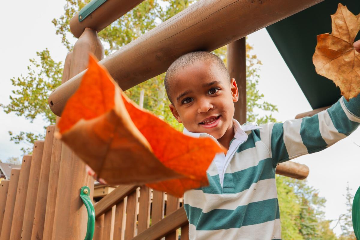 young black boy playing with leaves