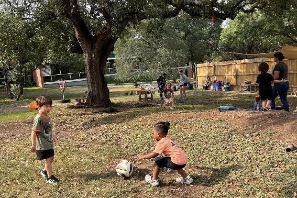children playing with a ball in an outdoor classroom setting
